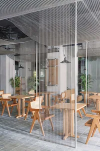 Modern restaurant interior with wooden tables and chairs, warm atmosphere, and comfortable seating for guests