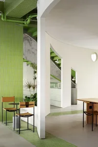 A bright and inviting interior space with a stairwell, two chairs, a potted plant, and natural light