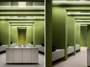 A modern bathroom with green walls, dual sinks, and decorative bowls, showcasing a clean and organized space with a focus on functionality and aesthetics