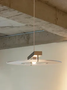A room with concrete walls and a metal light fixture with a circular shape, illuminating the space