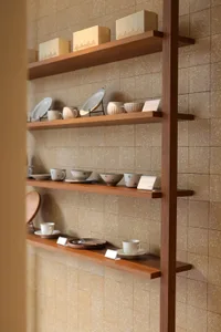 A wooden bookshelf with various dishes and cups on display, showcasing a collection of dishware