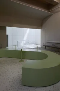 An open space with a large glass wall, green table bases, and a neutral setting, ideal for events or meetings