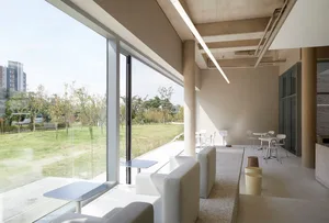 Open modern living space with white walls, large windows, and natural light, featuring multiple chairs and dining tables