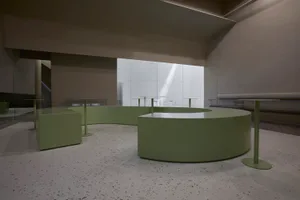 A modern cafe with green tables and chairs, white walls, and a clean, bright atmosphere