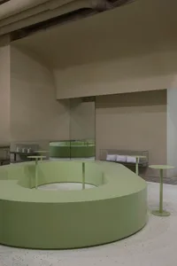 A modern interior design concept featuring green walls and floors, with tables and chairs in a spacious open area