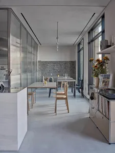 Modern kitchen and dining area with white cabinets, a dining table, chairs, and decorative vases in a clean and minimalist space