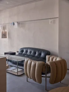 Empty minimalist living room with a couch, two chairs, and a dining table in the background, featuring a clean and minimalistic atmosphere