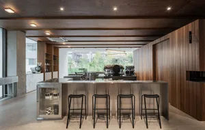 Cozy coffee shop interior with a wooden ceiling and walls, featuring a bar area with stools and chairs, and decorative items throughout