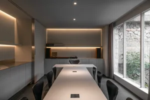 Empty kitchen with white walls, a black dining table, and wooden chairs, giving a clean and minimalistic atmosphere