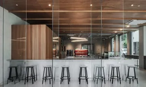 Bright coffee shop interior with glass walls, wooden tables, and black stools, featuring a modern and minimalist design