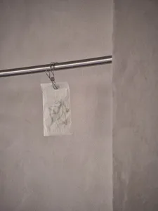 A dirty bathroom with a toilet paper holder and two rolls of toilet paper, with visible dirt on the walls
