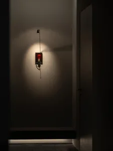 A dimly lit hallway with a door and a fire alarm with a red light, mounted to the wall