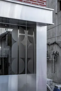 A modern building with a glass facade and three circular glass features, set against a neutral background