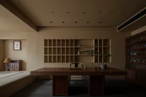 A calm dining space with a wooden table, chairs, and a potted plant, lit by natural light from a large window