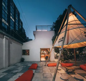 An outdoor dining area with a modern aesthetic, featuring a large umbrella, orange cushions, and a potted plant, set in a restaurant patio