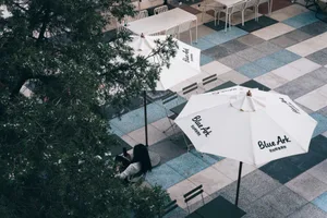 An outdoor dining area with tables, chairs, and umbrellas, featuring white tablecloths and a welcoming atmosphere