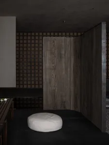 Warm and inviting room with a wooden floor, wooden doorway, and two benches, with a chair placed in the center