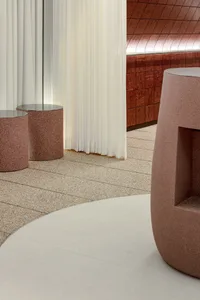 A large room with marble flooring, featuring three round tables and benches, in a modern and elegant atmosphere