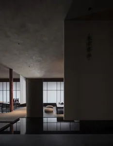 Empty living area with a large white wall featuring Asian writing, several chairs, and two couches, creating a calm and inviting atmosphere