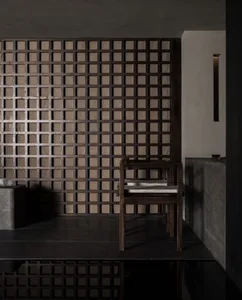 Modern bathroom with wooden walls and floors, featuring a sink, toilet, and two chairs, with a well-lit and inviting atmosphere
