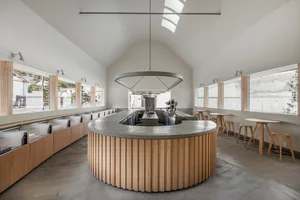Modern open kitchen with a large island, sink, chairs, and couches, surrounded by modern design elements
