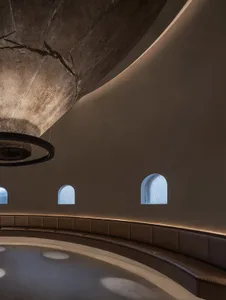 A large interior space with high ceilings, multiple windows, and benches for seating, creating a calm and inviting atmosphere