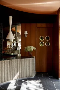 Warm and inviting restaurant interior with a counter, potted plants, and a vase of flowers, set for a pleasant dining experience