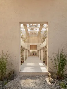 A calm hallway with a white tile floor and potted plants adding greenery and depth to the space