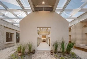 A modern building with a large open area, white walls, gray roof, and multiple windows providing natural light