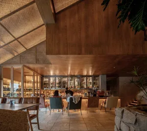 A social bar area with a dining table surrounded by chairs, bottles, and people enjoying a relaxed atmosphere