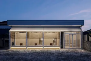 Empty modern building with concrete walls, large windows, and sparse furniture arrangement