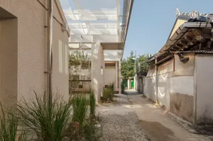 A modern house with a white exterior, a green door, and a patio area, surrounded by potted plants and decorative vases