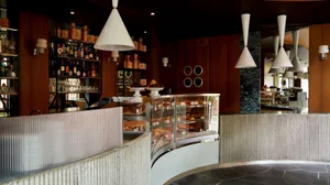A cozy restaurant interior with a counter displaying food and drinks, wine glasses, and a warm atmosphere