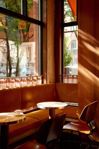 A modern dining area with several tables and chairs, featuring warm wood tones and a cozy atmosphere