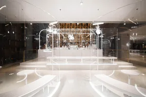 A modern cafe with white walls and floors, featuring benches and chairs for seating, creating an inviting and comfortable atmosphere