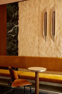 A warm and inviting living space with a yellow couch, furry wallpaper, two chairs, a dining table, and a vase, creating a cozy atmosphere