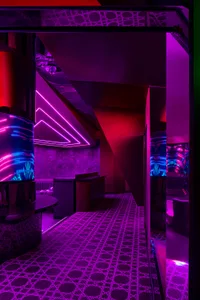Purple-lit bar area with a wooden counter and two sinks, modern design