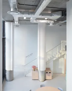 An open modern space with three tall pillars and two staircases leading to different levels, with a minimalist and modern design