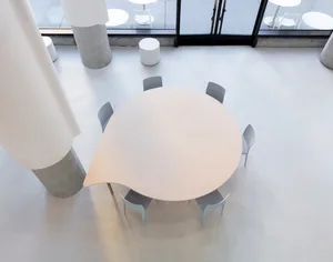 Empty dining space with a large wooden round table and multiple chairs, surrounded by additional dining tables in a spacious and inviting atmosphere