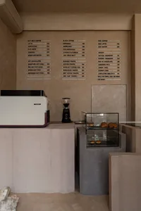 A cozy coffee shop interior with wooden furniture, cups, and a cake on a table, creating a welcoming atmosphere