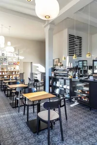 Inviting coffee shop interior with a bar, chairs, and dining tables, featuring cups and a warm atmosphere