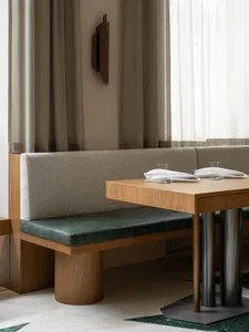 A dining area in a restaurant with a wooden table, chairs, and a vase, set for a meal in a cozy atmosphere