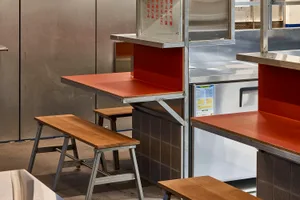 Industrial kitchen with a wooden countertop, metal stools, and two benches, featuring a functional and inviting space for food preparation and dining