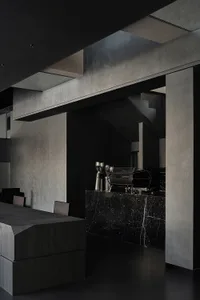 A dark and moody coffee shop interior with a black countertop, coffee machine, and cups, suggesting a nighttime setting
