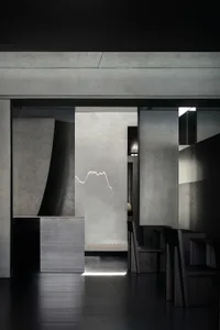 A modern restaurant dining area with multiple chairs and tables, grey walls, and dim lighting