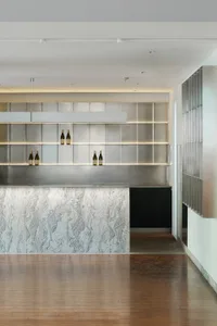 Elegant kitchen with a marble countertop, metallic bar, and wine bottles, featuring a modern and stylish design with metal and stone elements