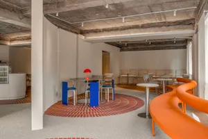 A modern cafe with a circular dining area featuring tables and chairs, inviting atmosphere, and clean lines, set against a tiled floor