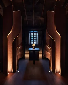 Warm and inviting interior space with wooden walls and floors, featuring a small lamp and large wooden doors