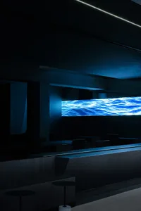 A darkened restaurant with a large blue waterfall as its centerpiece, surrounded by empty chairs and a sense of relaxation