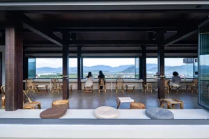 Outdoor dining area with wooden furniture, tables, and chairs, surrounded by a mountain landscape with a relaxed and inviting atmosphere